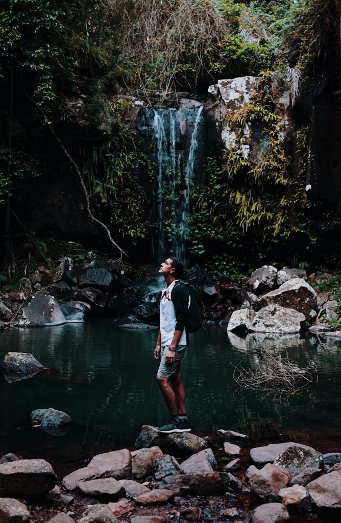 Man Standing on Rocks by Waterfall - Level Up Coaching